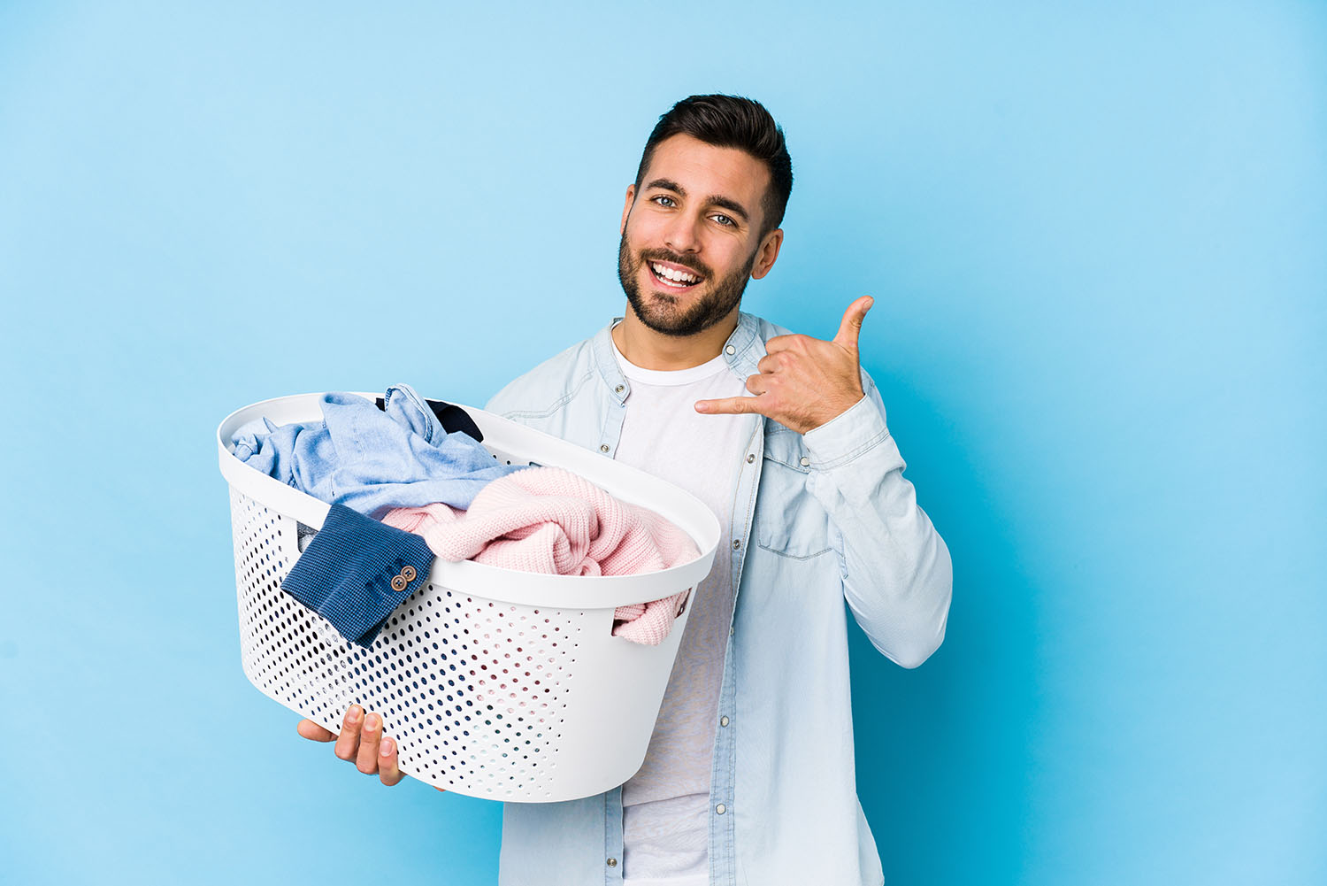 Young handsome man doing laundry isolated showing a mobile phone call gesture with fingers.